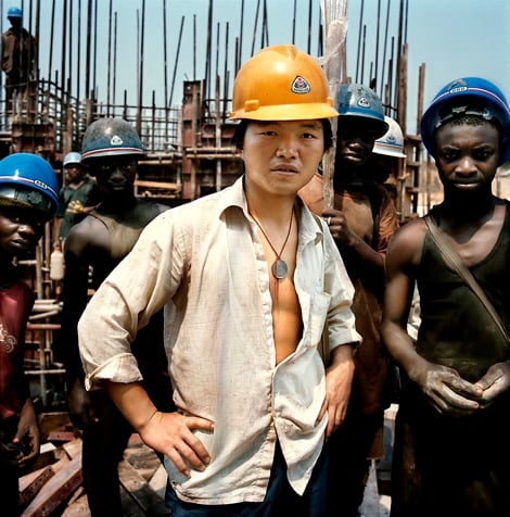 Republic of the Congo / Imboulou dam / 06.2007 On the building site of the Imboulou dam, Republic of the Congo, 200km north of the capital Brazzaville. In the foreground a Chinese worker of the China National Mechanical & Equipment corporation (CMEC) company, which in 2001 has obtained the contract. With its 120 megawatts, this power plant will double the national production of electricity and will give light to a large part of Congo. 400 Chinese technicians and qualified workers supervise a Congolese workforce of a thousand man, paid 3 dollars a day, that disappear as fast as they can find a better paid job. This, in part, explains the dam’s construction delay that has to be absolutely terminated by 2009, the year of the next Congo elections. CMEC requires the Chinese workers to wear yellow and the Congolese blue hardhats. © Paolo Woods / Anzenberger